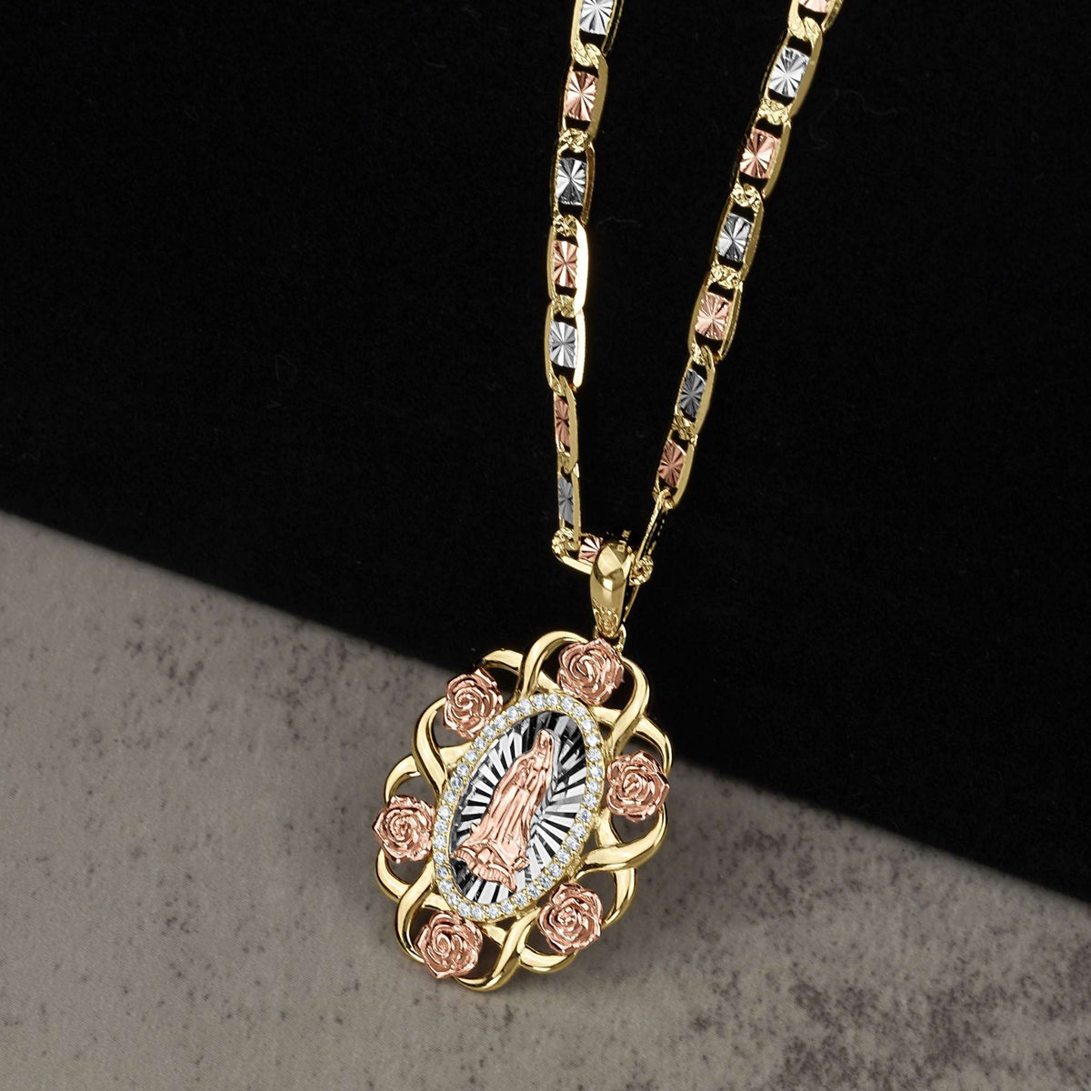 Gold necklace featuring a Virgin Mary pendant with rose gold accents on a dark textured background.