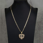 A gold chain necklace with a heart-shaped pendant on a black jewelry bust.