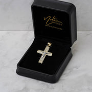 Gold and CZ cross pendant inside an open black jewelry box with gold logo branding.