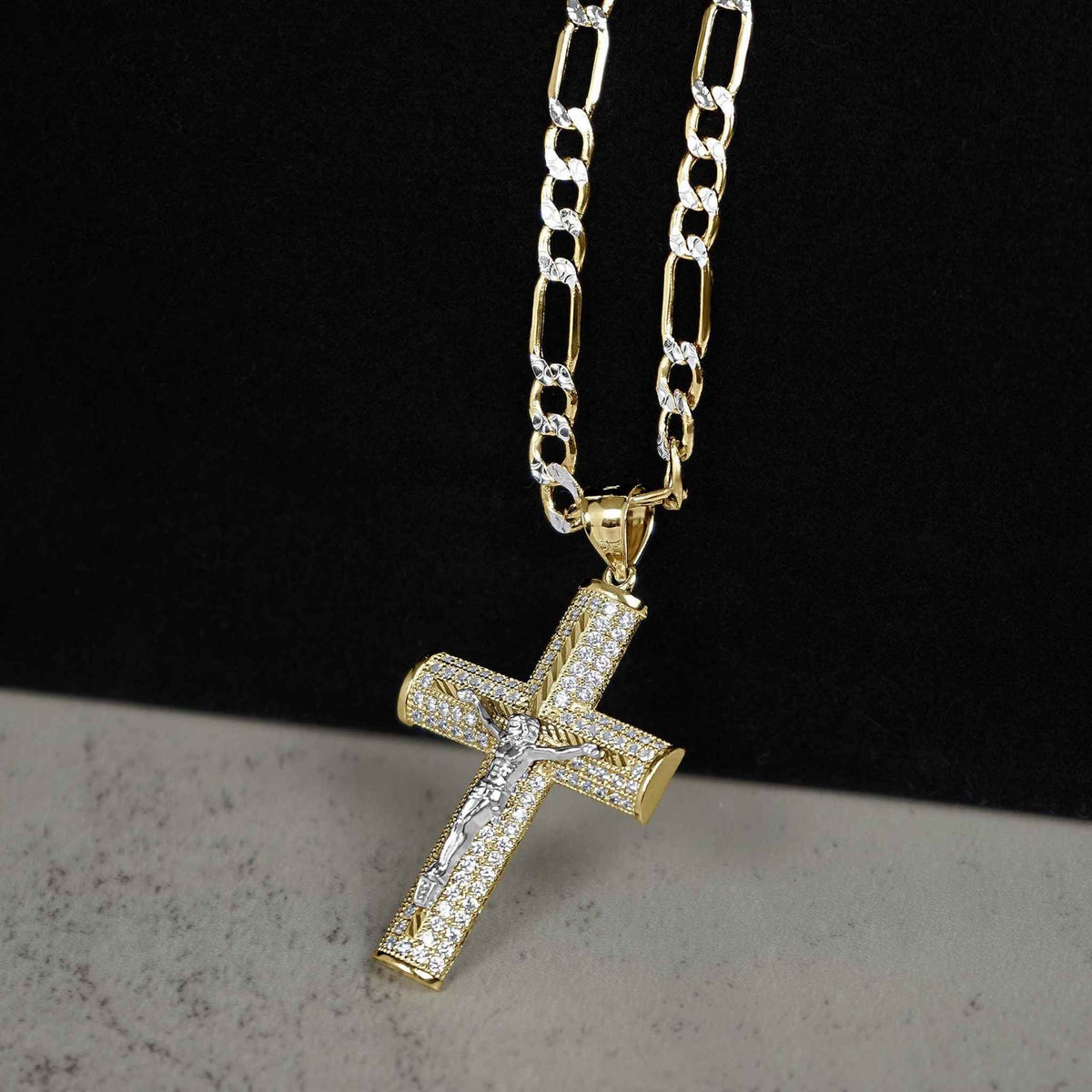 Gold Yelca crucifix pendant with cubic zirconia stones on pave Figaro chain necklace.
