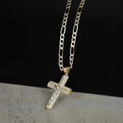 Gold crucifix cross pendant paved with cubic zirconia, hanging from a gold Figaro chain.