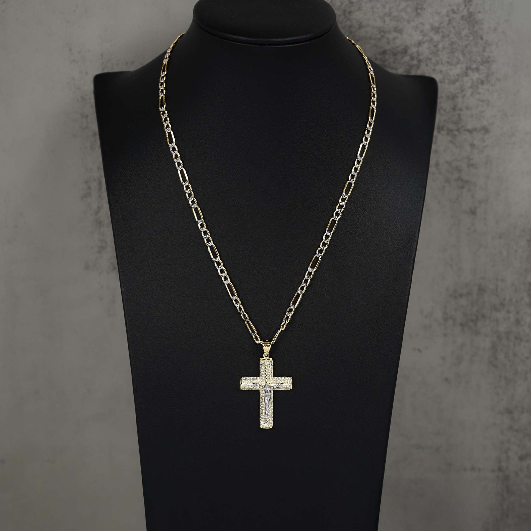 Gold crucifix pendant encrusted with cubic zirconia, displayed on a black jewelry bust.