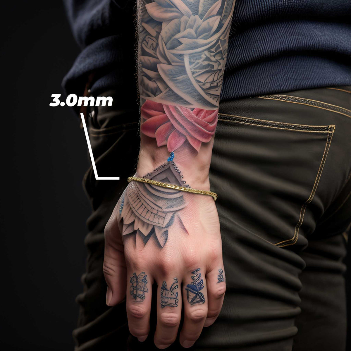 Model wearing a 3.0mm yellow gold wheat palm chain bracelet on tattooed wrist