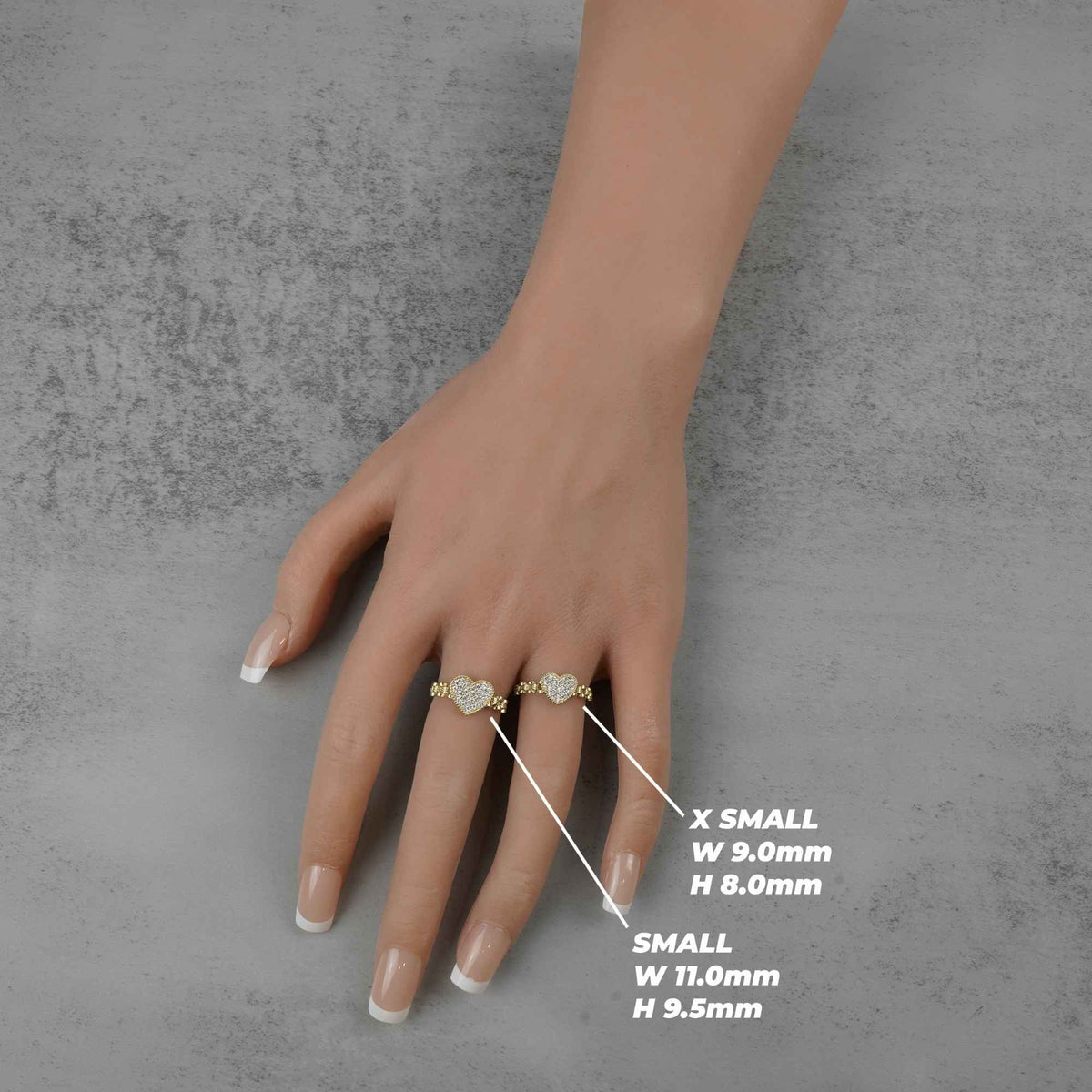 Hand wearing two 10k heart shaped rings with size measurements.