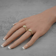 two 10k Gold ring with heart shaped designs on a hand against a gray background