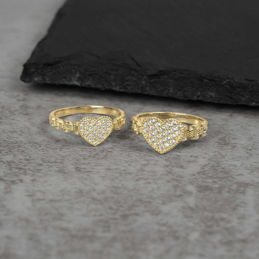 Two 10k gold heart shaped rings with Cubic Zirconia accents on a gray surface.