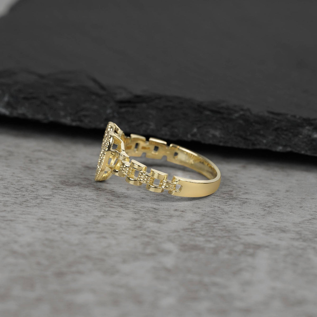 10k Gold ring with intricate design on a gray surface