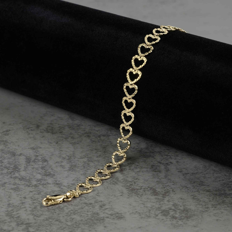 10k yellow gold Amori open heart nugget bracelet draped on a black roll display.