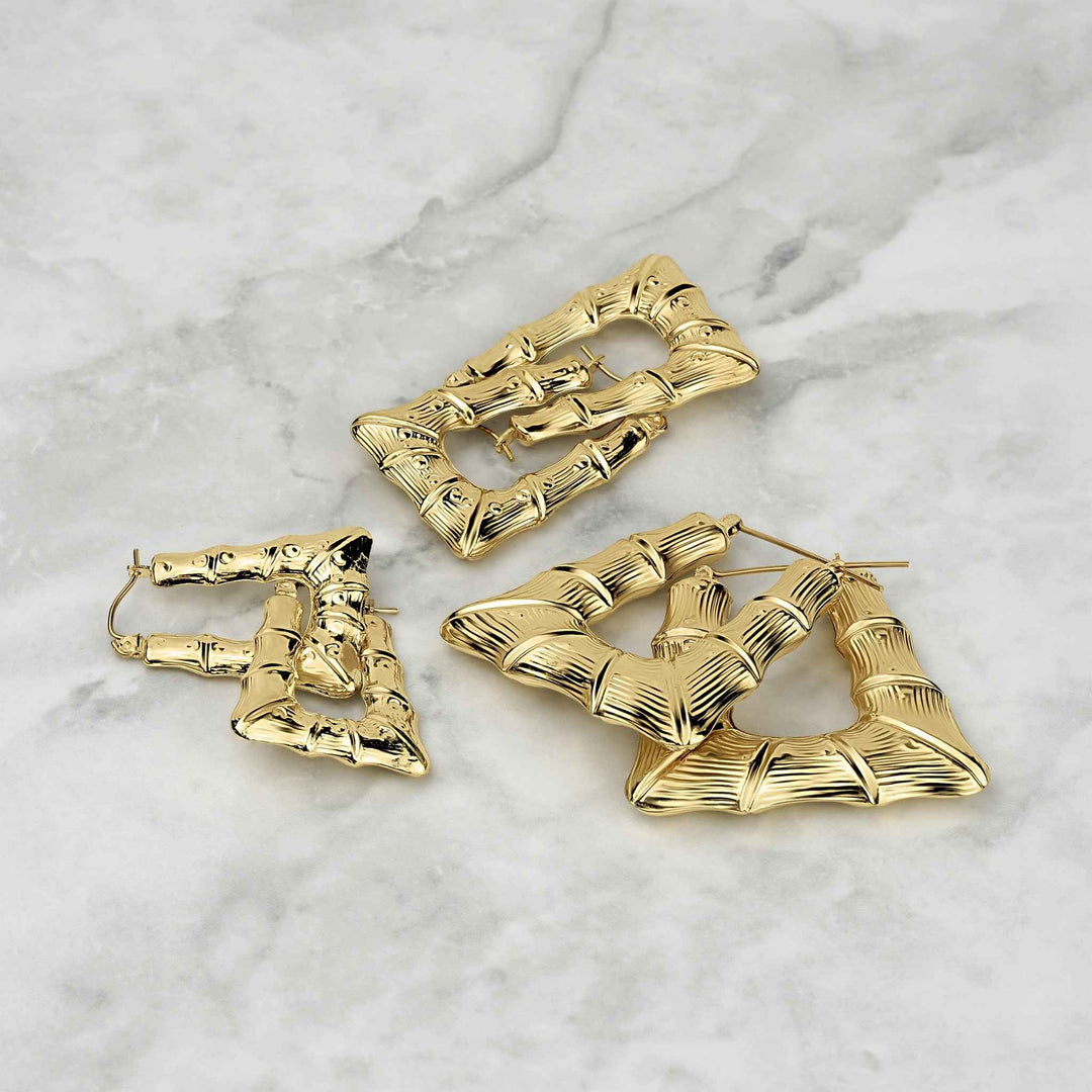 Three different sizes of polished 10k gold bamboo-textured square hoop earrings on marble.
