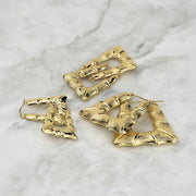 Three different sizes of polished 10k gold bamboo-textured square hoop earrings on marble.
