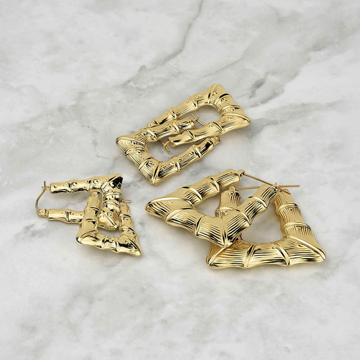 Three different sizes of polished 10k gold bamboo-textured square hoop earrings on marble.
