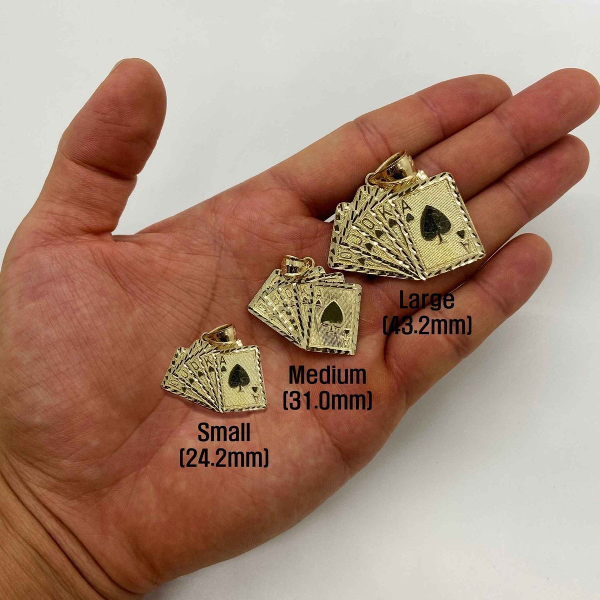 Small, Medium, and Large 10k gold Royal Flush pendants held in an open hand