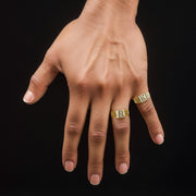 Hand wearing two 10k gold square initial rings against a black background.