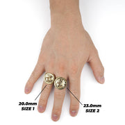 Two gold globe signet rings in different sizes worn on a hand with measurements.