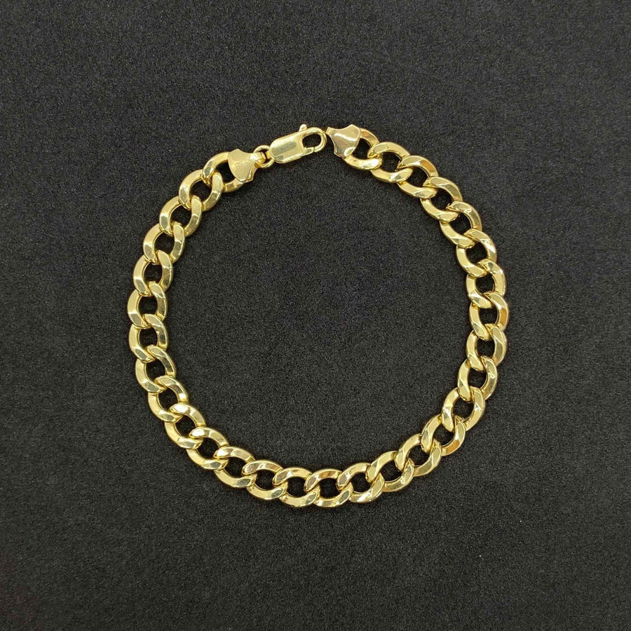 Polished 10K yellow gold Cuban curb link bracelet with lobster clasp on dark background