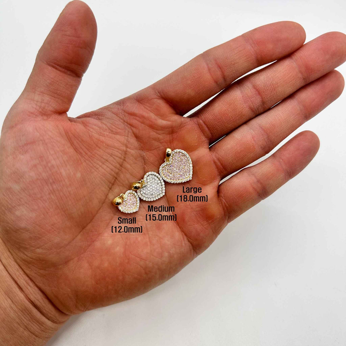 Three 10k gold heart pendants held in hand with size labels in millimeters.