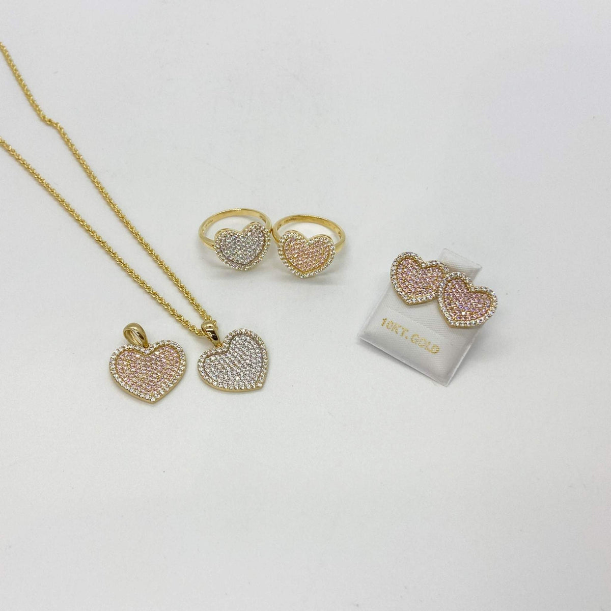 Matching gold heart jewelry set with necklace, rings, and earrings in pink and white CZ.