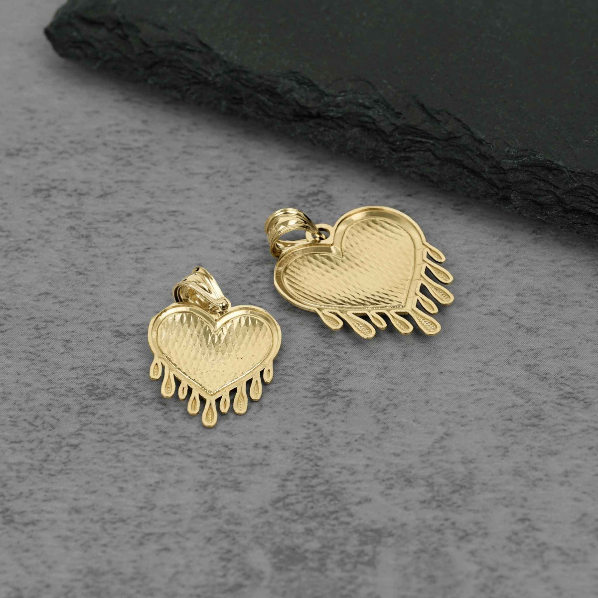 Back view of two 10k gold dripping heart pendants showing hollow reverse setting.