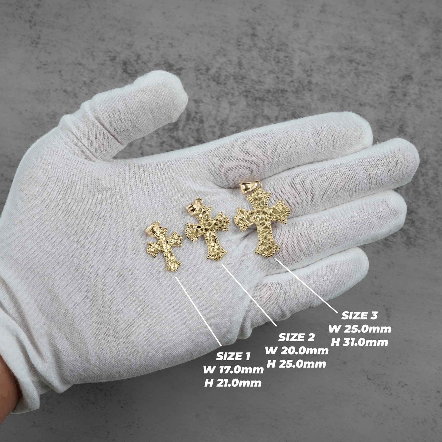 Three gold cross pendants on a gloved hand showing size dimensions.