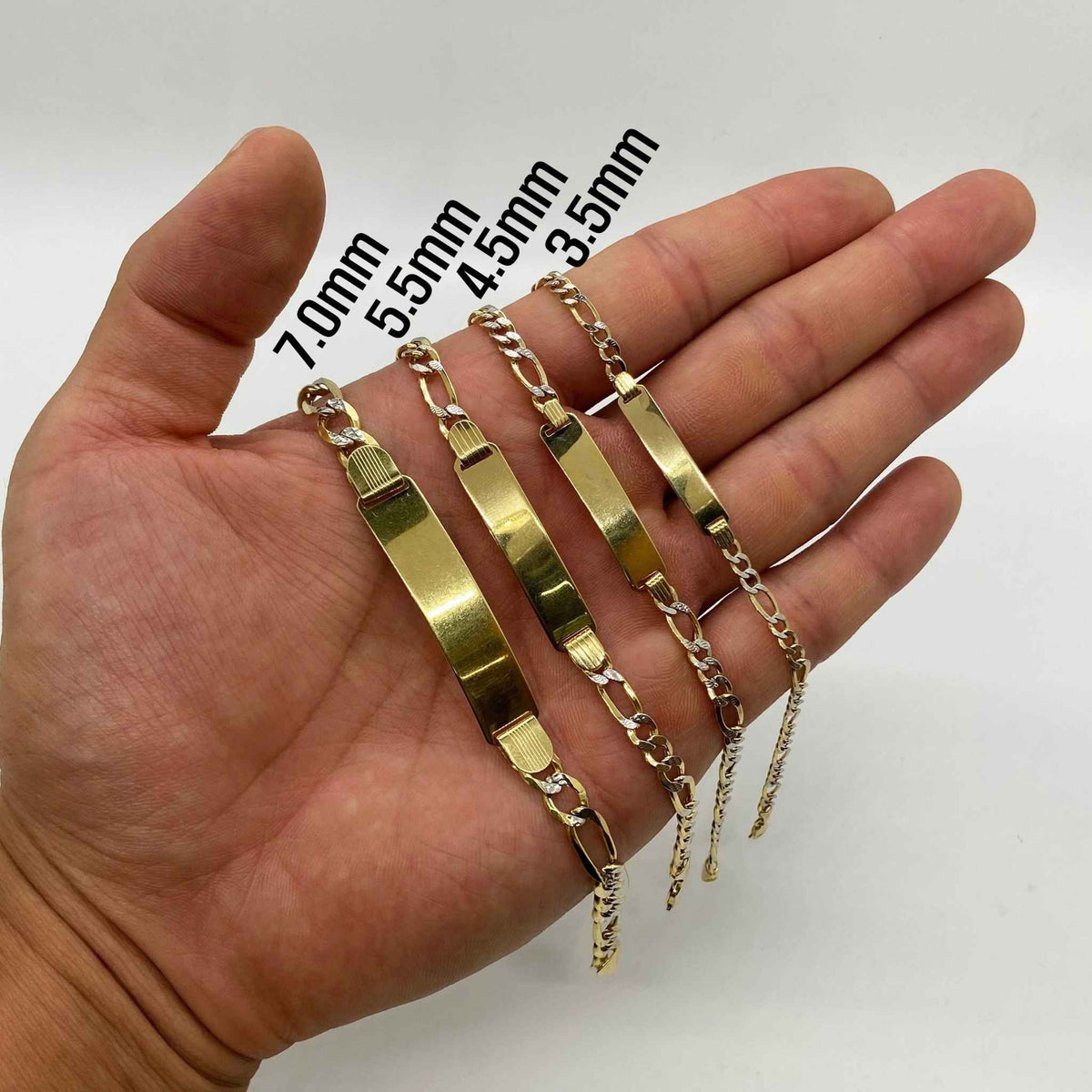 Hand holding four 10k gold Figaro link ID bracelets labeled 3.5mm to 7.0mm