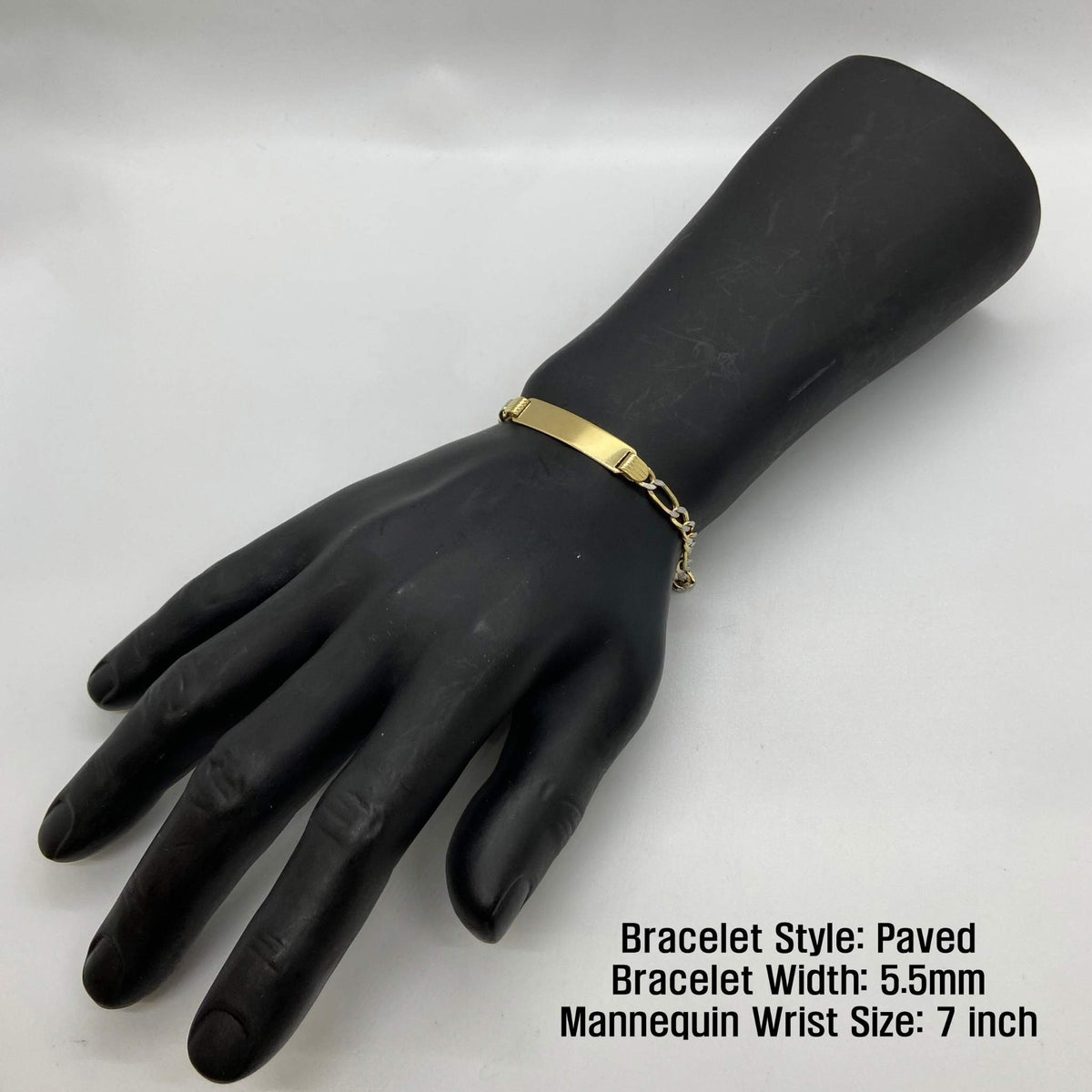 Paved 5.5mm gold Figaro ID bracelet shown on a 7-inch mannequin wrist.