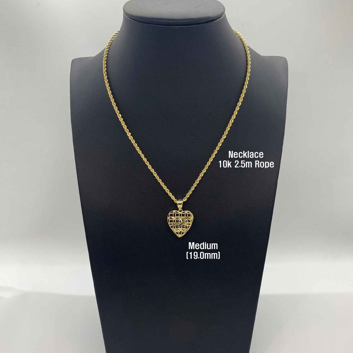 Medium gold filigree heart pendant necklace displayed on black jewelry bust mannequin.