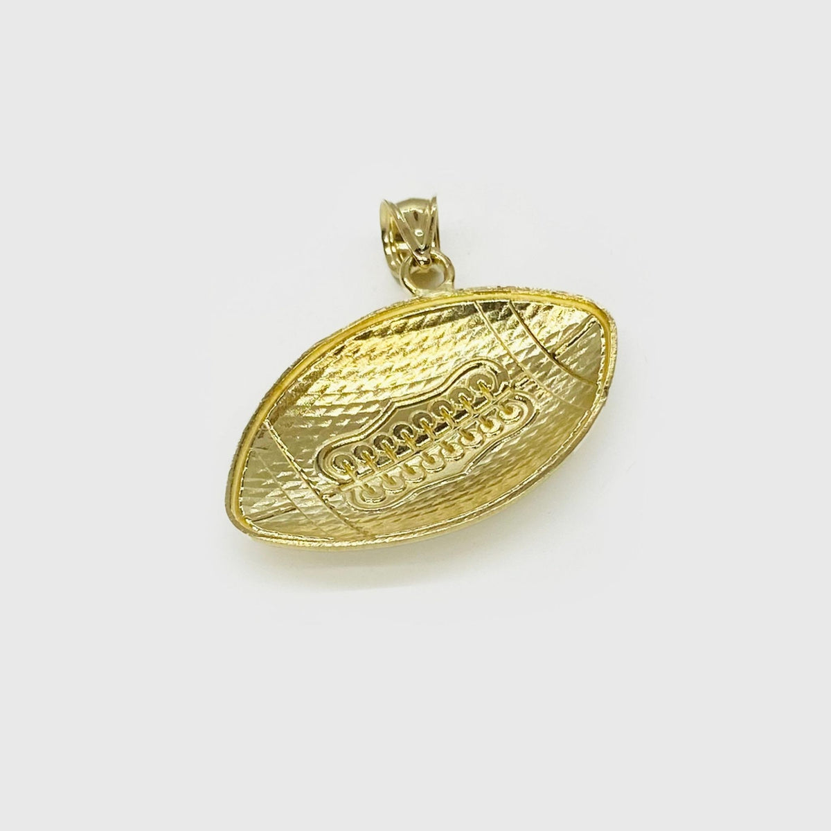 Back view of a textured 10k yellow gold football pendant on a gray background.