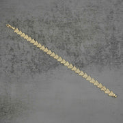 10k gold Forev nugget butterfly link bracelet laid diagonally on a gray surface.