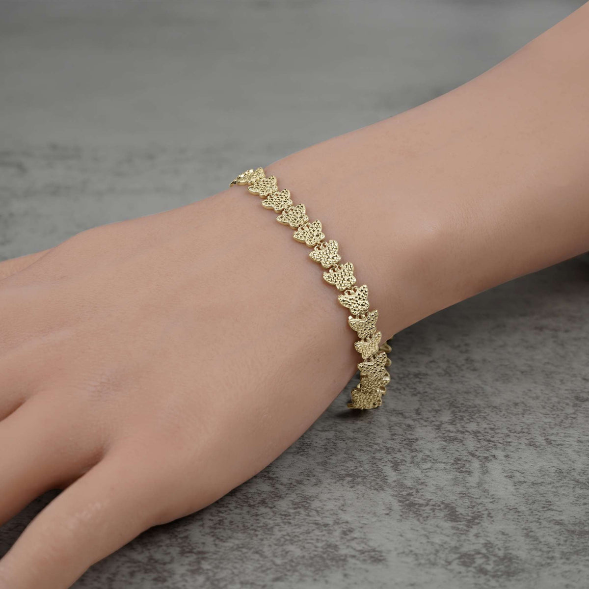 Model wearing a 10k gold Forev nugget butterfly link bracelet on their wrist