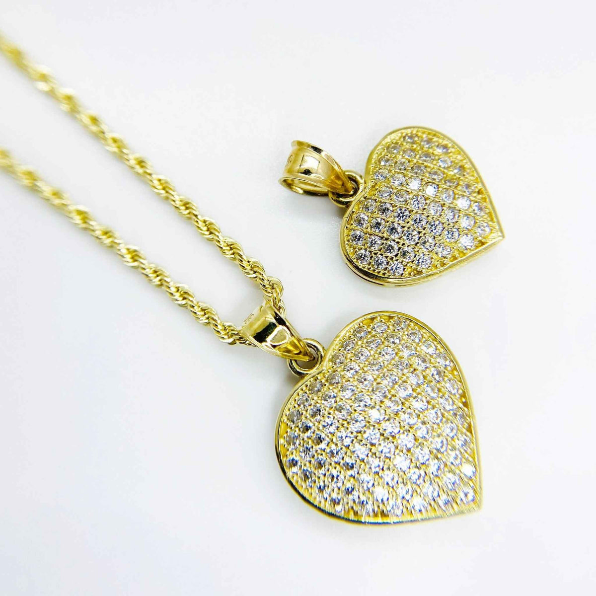 Pair of 10k gold iced-out Frida convex heart pendants featuring clear pavé CZ stones