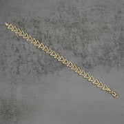 10k gold nugget butterfly link bracelet laid flat diagonally on a gray surface.