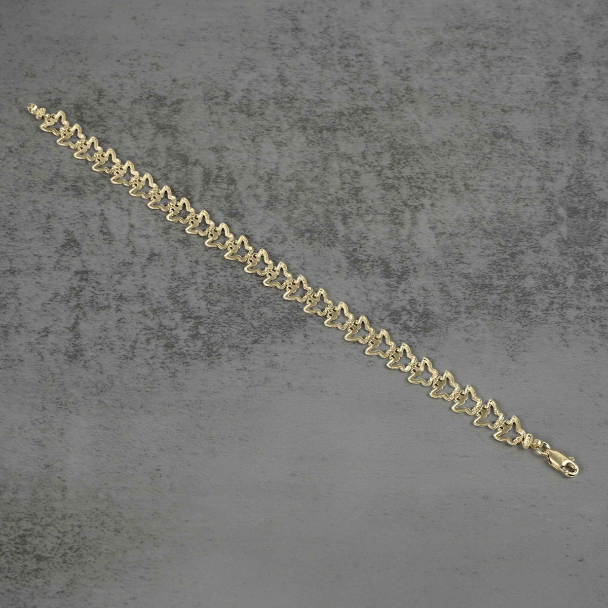 Back view of a 10k gold nugget butterfly link bracelet flat on gray surface.