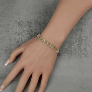 Top-down view of a 10k gold Amori nugget butterfly link bracelet on a wrist.