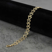 10k gold nugget butterfly link bracelet draped on dark velvet and gray surface.