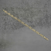 Top-down view of a 10k yellow gold Amori nugget heart and cross link bracelet.