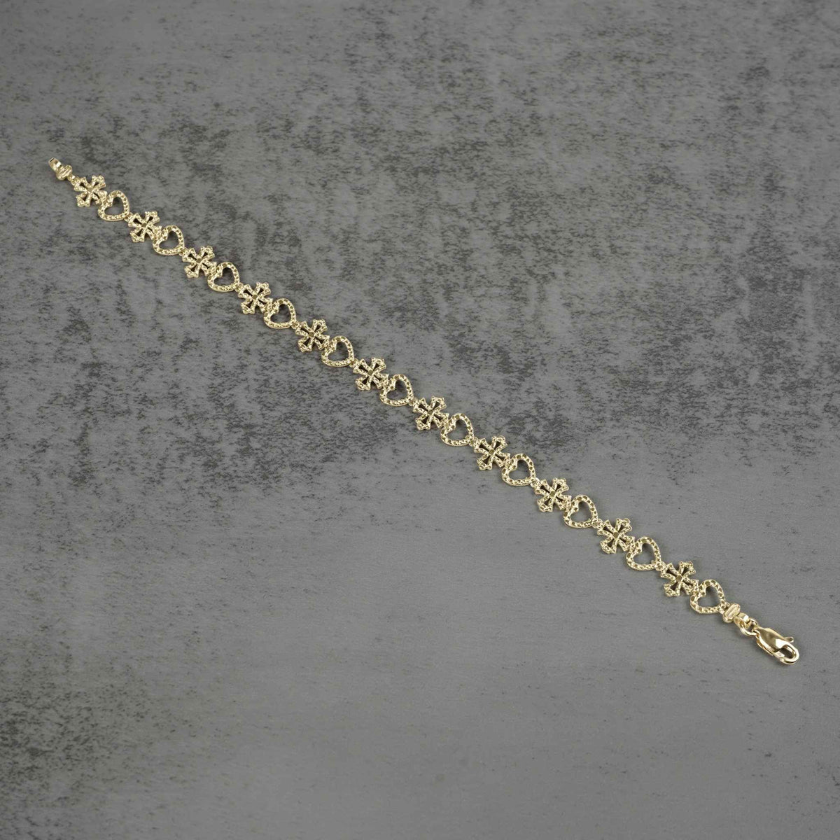 Top-down view of a 10k yellow gold Amori nugget heart and cross link bracelet.