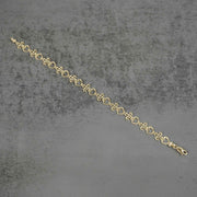 Top-down view of a 10k yellow gold Amori nugget heart and cross link bracelet.