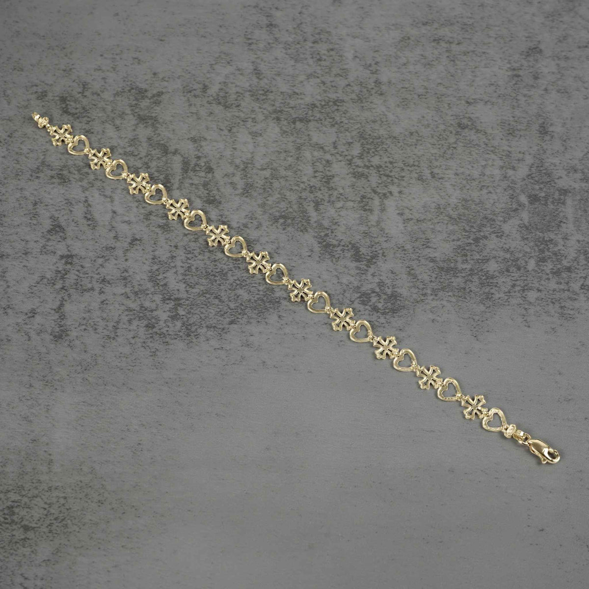 Top-down view of a 10k yellow gold Amori nugget heart and cross link bracelet.