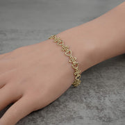 Model wearing a 10k yellow gold Amori nugget heart and cross link bracelet.