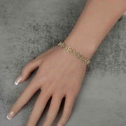 Model wearing a 10k yellow gold Amori nugget heart and cross link bracelet.