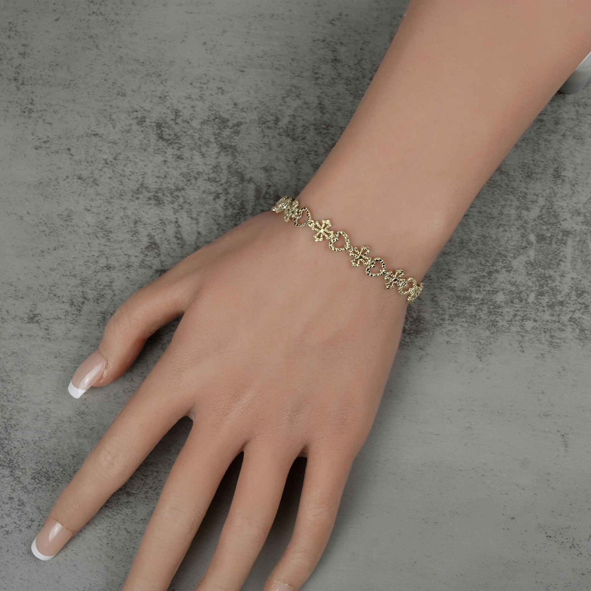 Model wearing a 10k yellow gold Amori nugget heart and cross link bracelet.