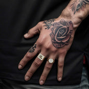 Men's 10k gold hexagon signet ring styled on a model with hand tattoos
