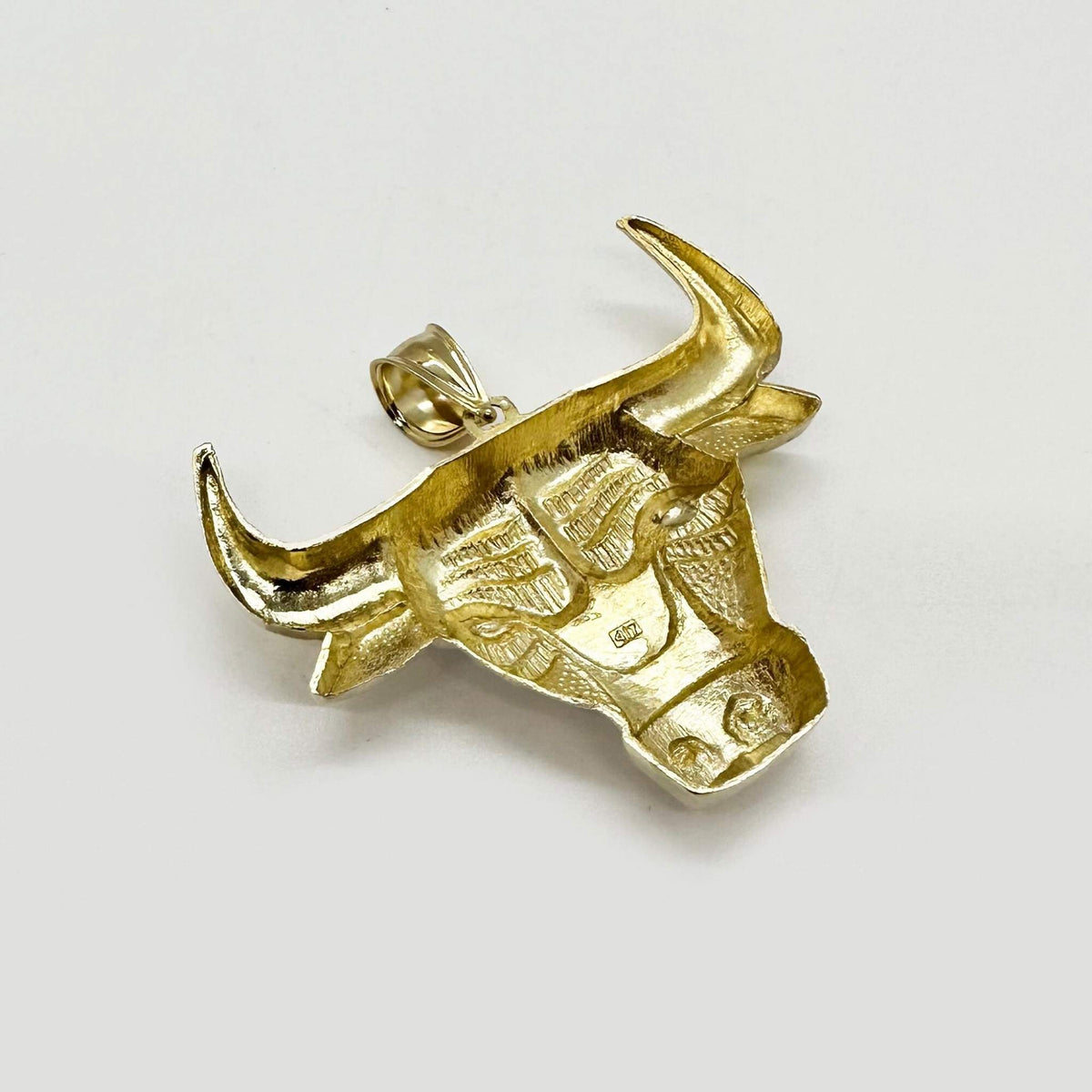 Back view of a 10k yellow gold bull head pendant showing textured underside detailing.