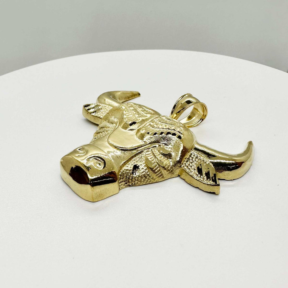 Angled view of a 10k yellow gold bull Taurus pendant showing polished horns.