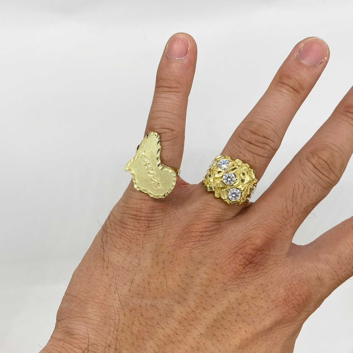 Hand wearing two gold rings one nugget style one textured designs 