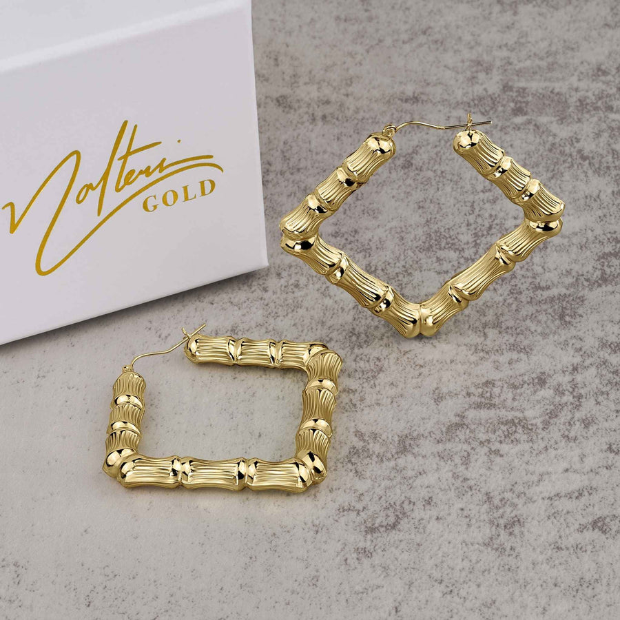 Pair of 10k yellow gold rhombus-shaped bamboo hoop earrings resting beside a Nolters jewelry box.