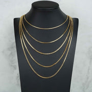 Four 10k yellow gold solid box chain necklaces layered on a black jewelry mannequin bust.