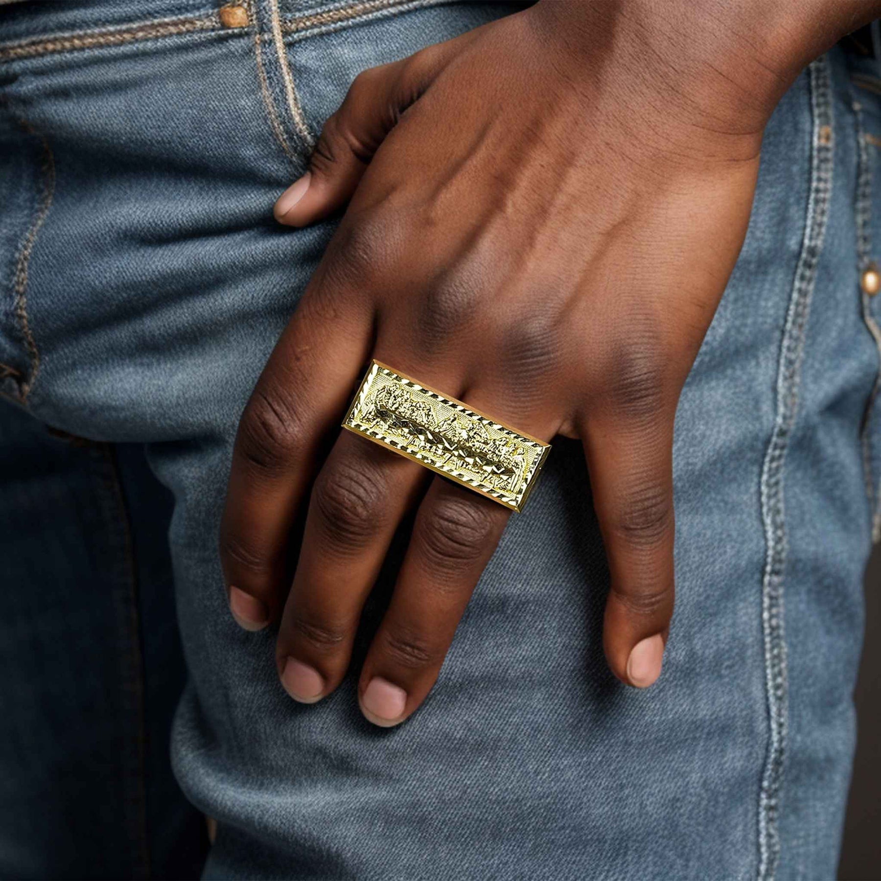 A man’s hand wearing a 10k gold classic Last Supper two-finger statement ring.