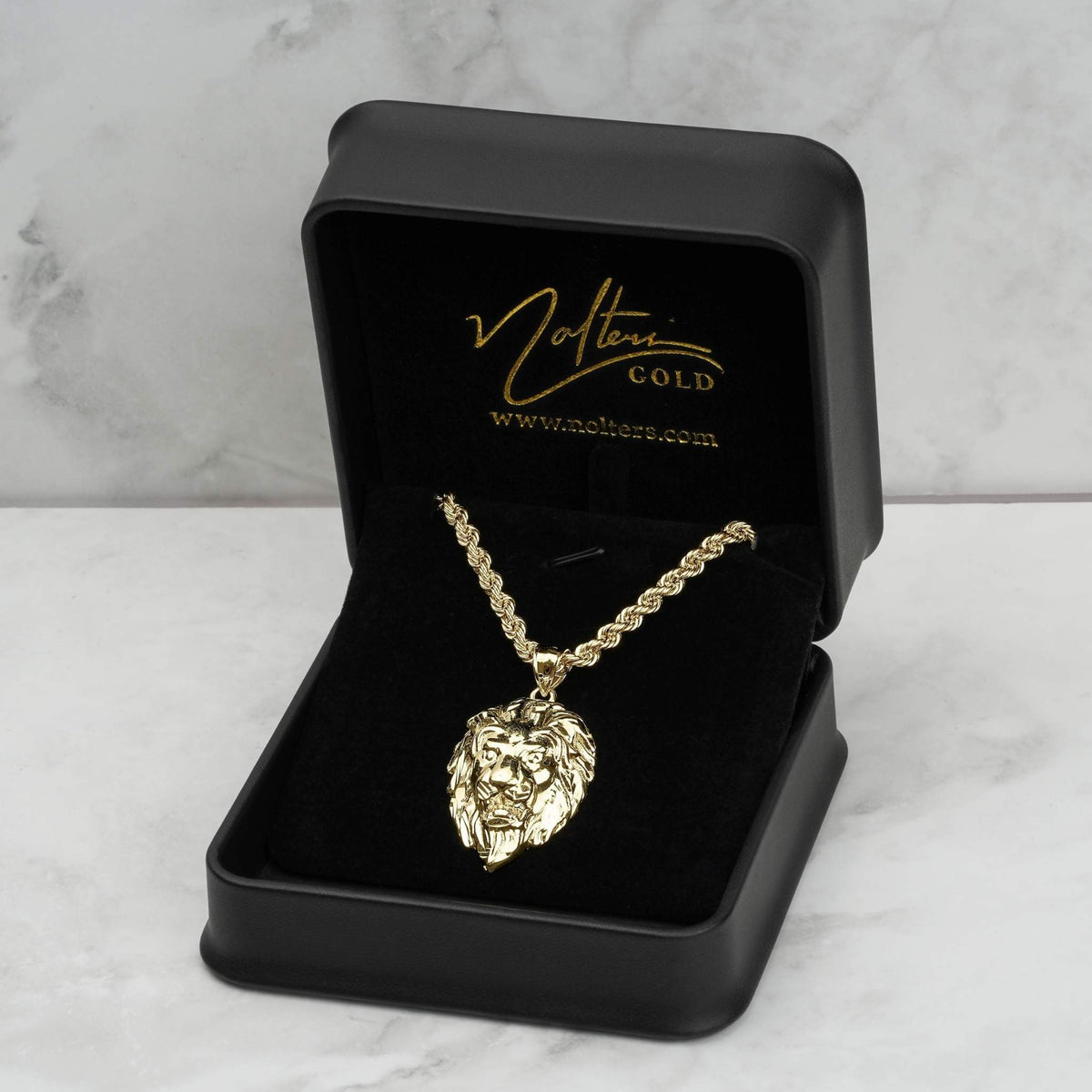 10k gold lion head pendant necklace displayed in a black jewelry box on marble.