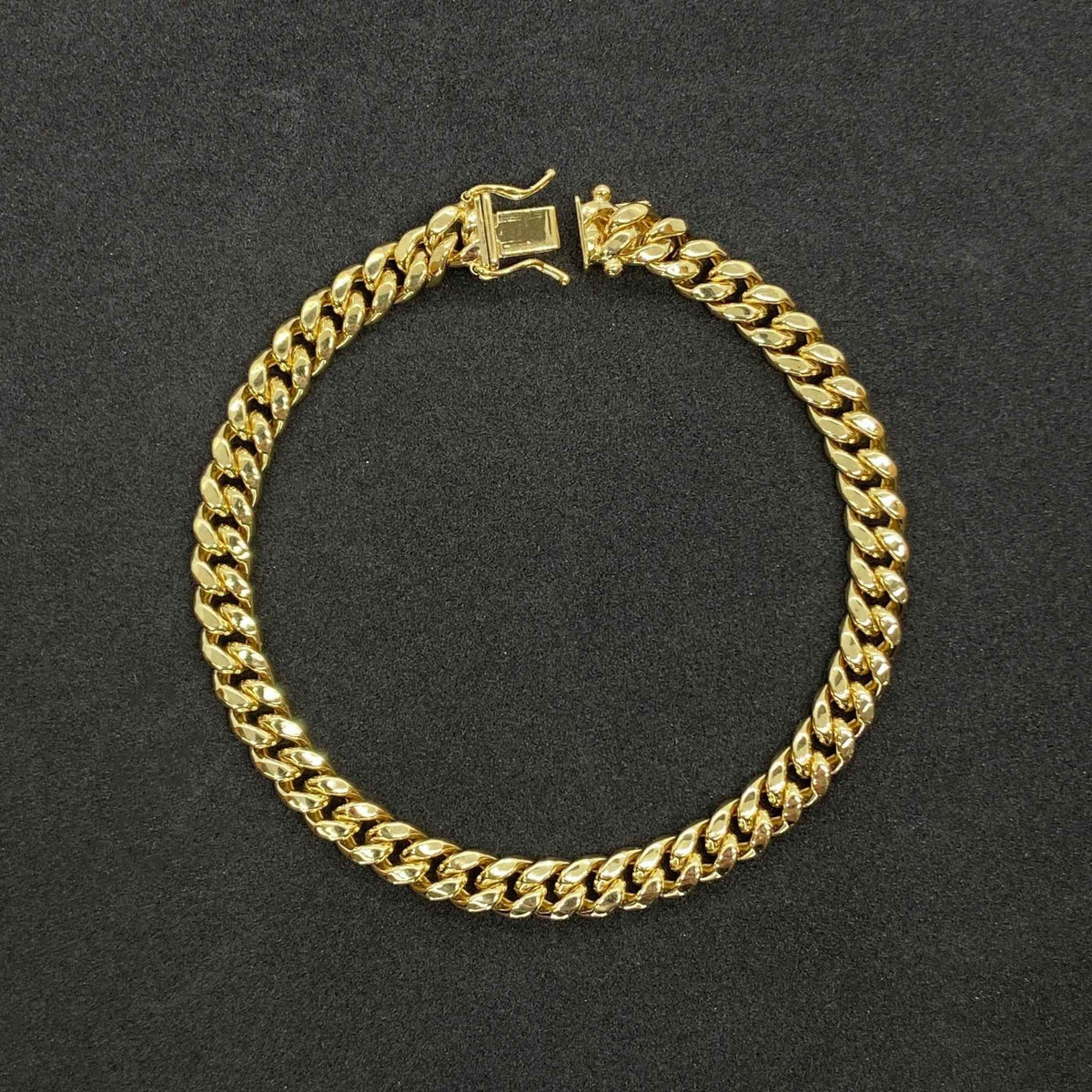 Solid 10k yellow gold Miami Cuban link bracelet with box lock clasp on dark background.